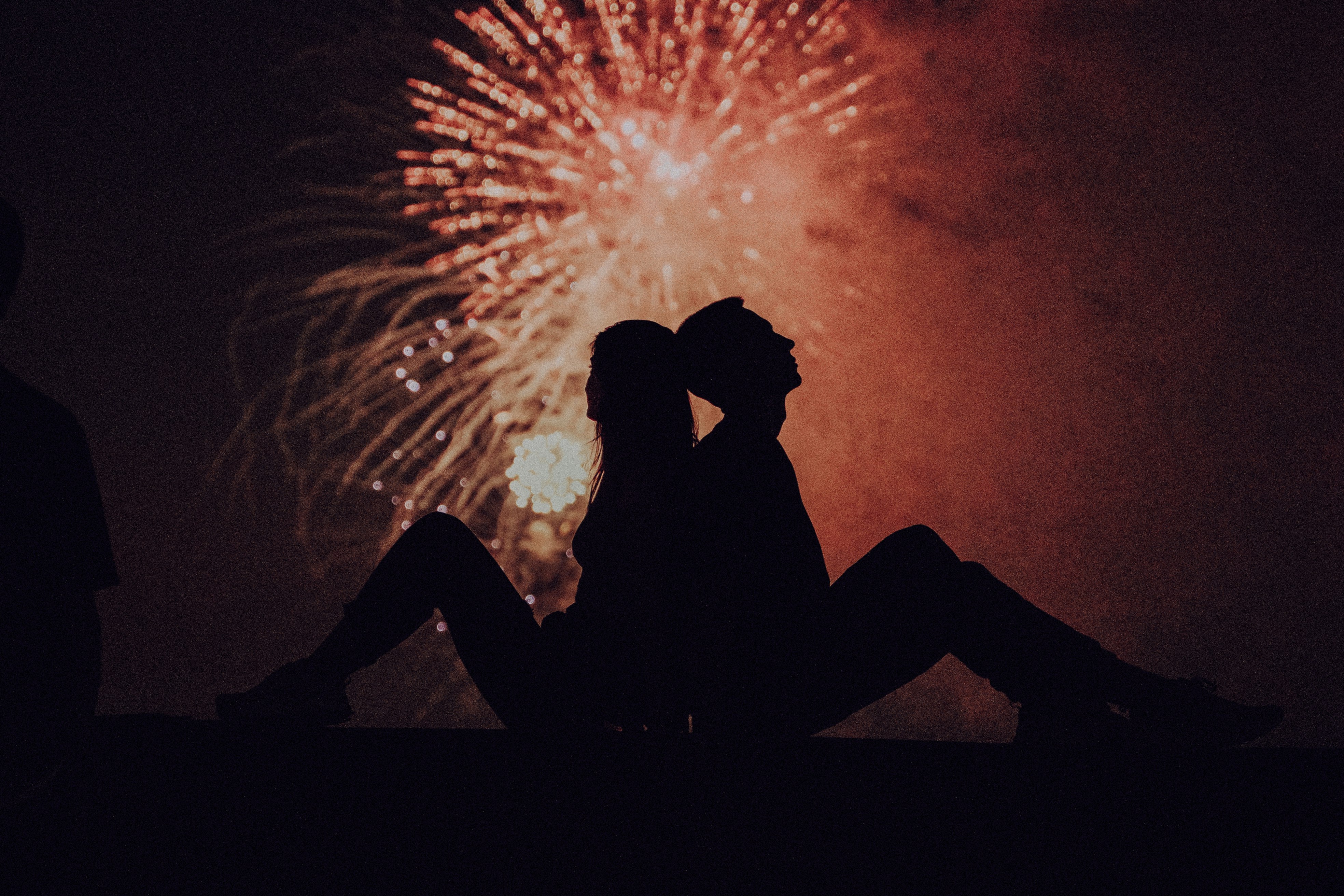 silhouette of man and woman kissing under fireworks